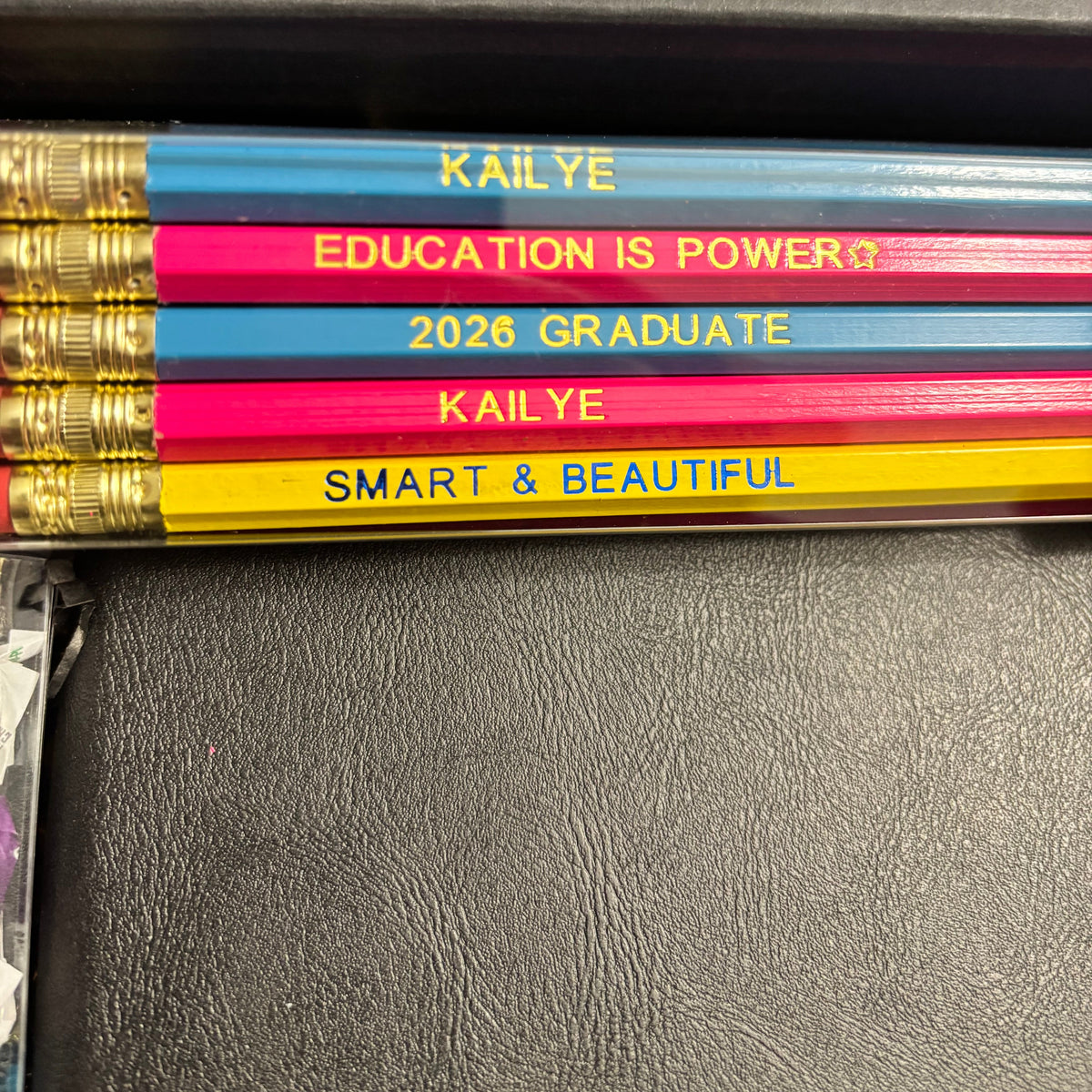 Colorful pencils with personalized text on a dark surface