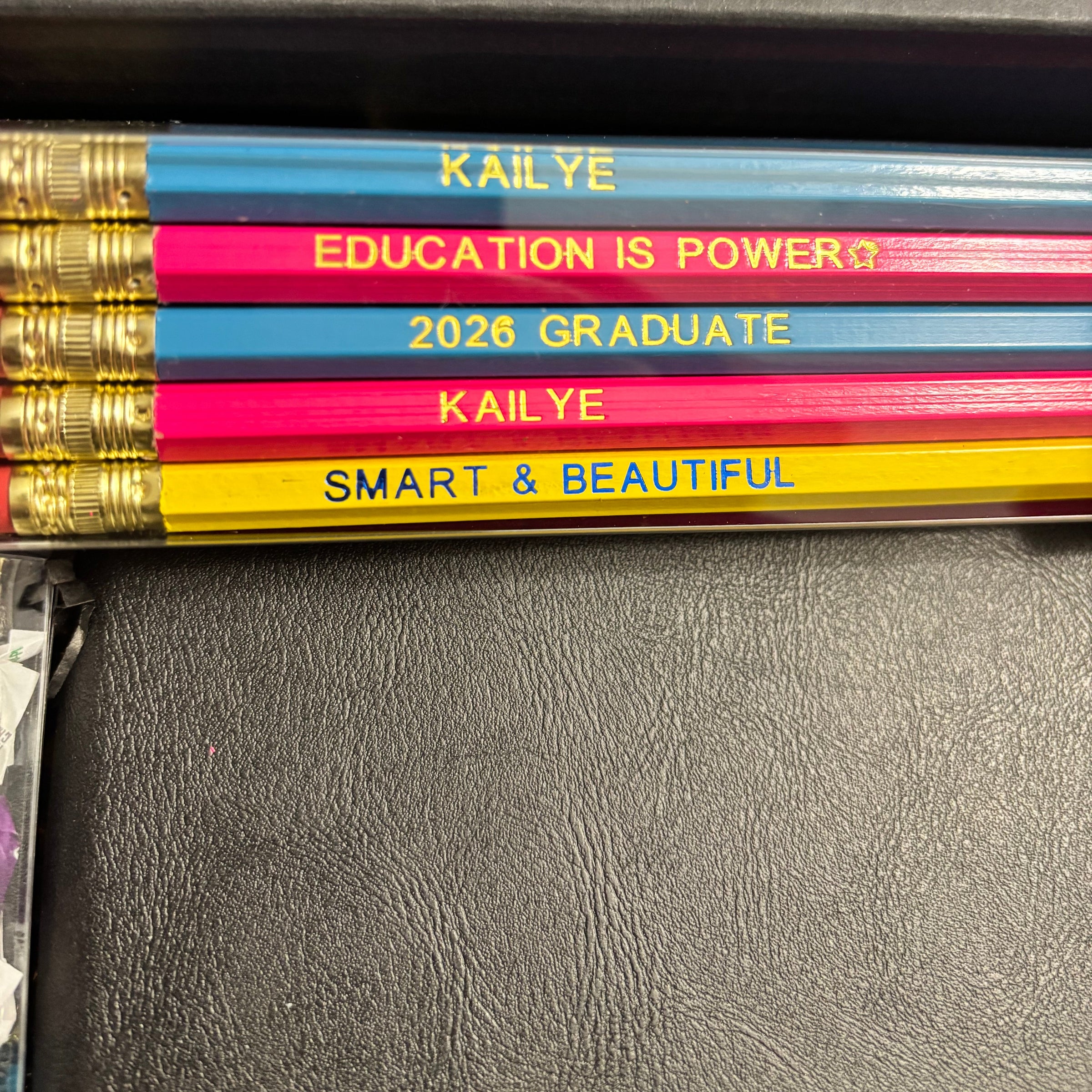 Colorful pencils with personalized text on a dark surface